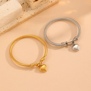 Fashionable gold and silver twisted cable bracelets with heart charms on stone props