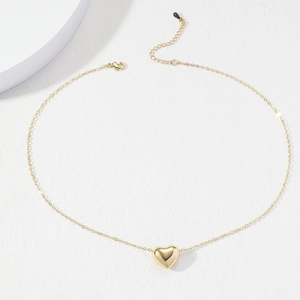 Minimalist golden heart pendant necklace on white textured background, adjustable chain