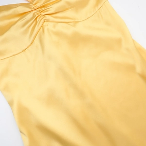 Macro shot of elegant yellow satin fabric featuring detailed handcrafted pleats and textures