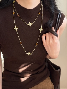 Détail d'un collier vintage doré avec croix en diamants et perles œil de tigre sur modèle