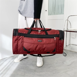 Detail of burgundy nylon travel bag showing the dual metal zippers and large main pocket