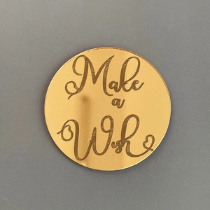 Vue détaillée d'un cake topper rond doré en acrylique avec gravure Make a Wish.