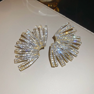 Macro shot of fan-shaped gold earrings with radiating crystal pave setting details