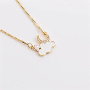 Detailed view of crescent moon and white enamel cloud pendant on a golden box chain
