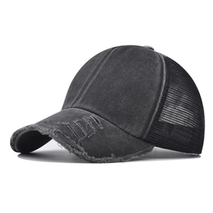 Detail showing distressed holes on brim and breathable mesh of black cotton trucker hat