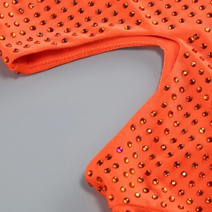 Détail macro du tissu orange orné de strass brillants avec une texture en maille fine
