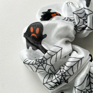 Macro view of Halloween scrunchie with white fabric, black ghosts and spider web patterns