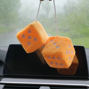 Detail of plush orange car dice hanging with purple heart patterns and white string