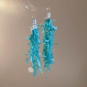 Detail of lake blue fringe earrings with silver square studs and white sequins
