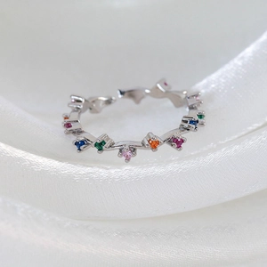 Macro shot of silver adjustable ring featuring tiny multi-colored micro-set zircons on silk
