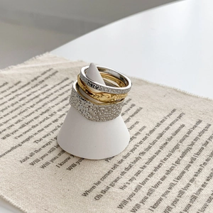 Set of four stacked lava texture rings in gold and silver finish on a display stand