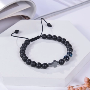 Close-up of 8mm black matte stone beaded bracelet with silver cross pendant on white stand