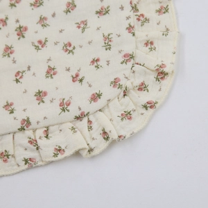 Detailed macro view of pure cotton gauze fabric with pink floral patterns and ruffle edges
