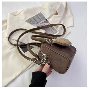Detail of brown faux suede handbag with plush trim, silver zippers, and adjustable strap