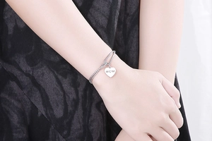 Close-up of double-layer stainless steel bracelet with heart charm engraved with MOM