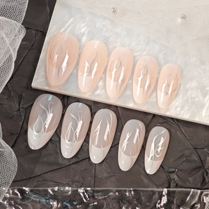 French almond press-on nails with silver flame patterns on nude and white bases