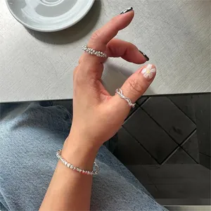 Close-up of minimalist S925 sterling silver rings and bracelet on a metal surface
