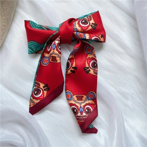 Red silk satin skinny scarf with cartoon tiger pattern on white folded fabric