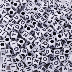 Close-up of white acrylic cube letter beads with black printed capital letters for DIY crafts