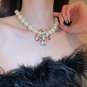 Close-up of Baroque pearl necklace with a colorful gemstone-encrusted golden cross pendant