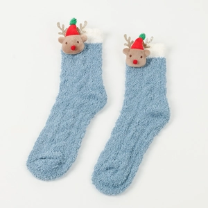 Nahaufnahme blauer Plüschsocken mit süßer Weihnachtsrentier-Puppe auf weißem Grund