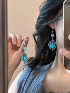 Detailed view of vintage bohemian oval blue resin drop earrings on model