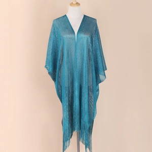 Detail of blue shimmering knit shawl featuring elegant fringe hem on a studio mannequin