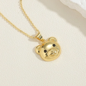 Close-up of a golden teddy bear pendant necklace on a natural textured background