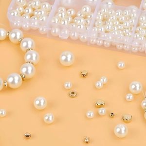 Close-up of white ABS imitation pearls and golden spacer beads for DIY jewelry making