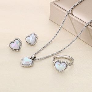 Silver heart jewelry set with necklace, ring, and earrings on a textured background