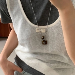 Detailed close-up of a silver cross emblem on a dark tiger eye padlock pendant necklace