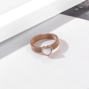 Detail of rose gold mesh ring featuring a white heart shell inlay on a geometric surface