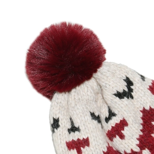 Detailed view of beige knit beanie with red geometric patterns and faux fur pom-pom