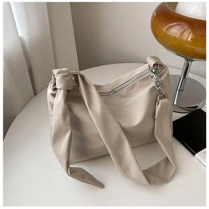 Detail of minimalist beige canvas shoulder bag with silver chain and knotted strap