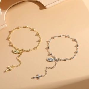 Detail of gold and silver cross rosary bracelets with Madonna pendants on warm background