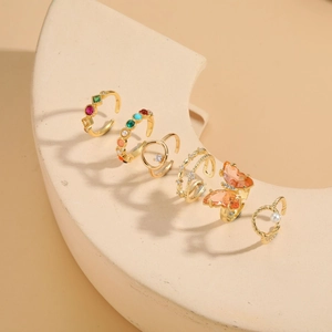 Detail of gold butterfly and pearl rings set displayed on a beige curved prop