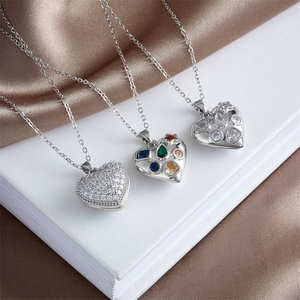 Three elegant heart pendant necklaces with crystals on white book and brown satin