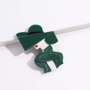 Detail of green acrylic brooch showing a fashionable lady wearing a wide-brimmed hat