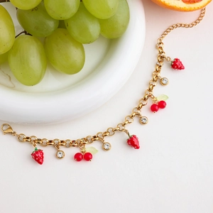 Detail of gold bracelet featuring red strawberry and cherry charms with crystals