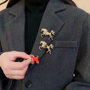 Close-up of three vintage horse brooches with enamel and crystals on a gray suit jacket