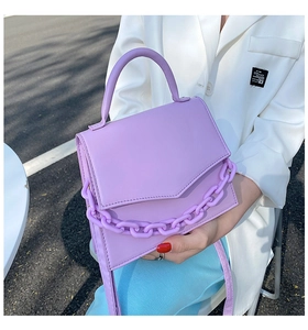 Street style shot of a trendy purple leather crossbody bag with chunky chain detail