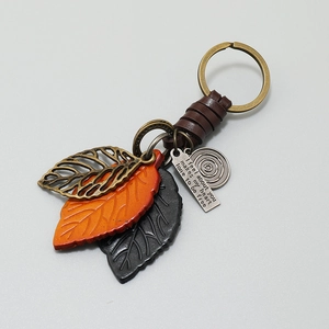 Retro braided leather keychain with bronze leaf charms and engraved metal tag detail