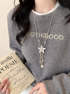Detail of bohemian star pendant necklace with leather cord and silver tassels on grey sweater