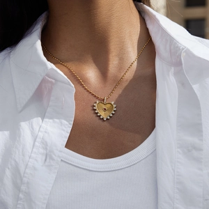Macro detail of gold heart necklace with red gemstone and radiant sunburst texture