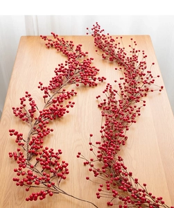 Close-up of realistic red berry stems for holiday home decor on a light wood surface