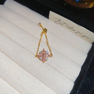 Makro-Detail des verstellbaren Goldblumenrings mit rosa Kristallen auf Samttablett