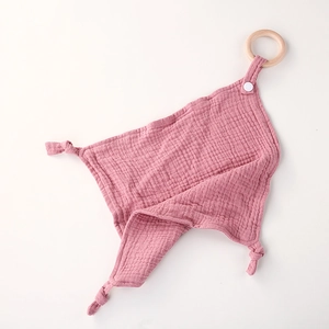 Detalle de arrullo de muselina rosa con aro de madera natural y esquinas con nudo suave