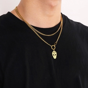 Detail of layered gold stainless steel necklace with hollow skull pendant on model