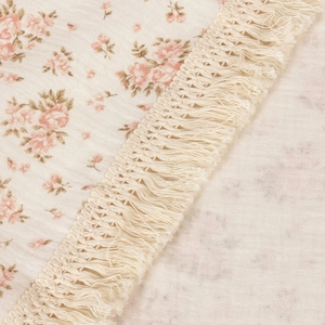 Close-up of double-layer cotton gauze baby blanket with floral print and tassel edges