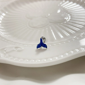 Macro detail of blue whale tail tongue stud made of stainless steel on white ceramic